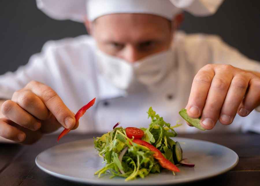 A chef garnishing a beautifully plated dish in a restaurant, representing the importance of digital marketing for restaurants.